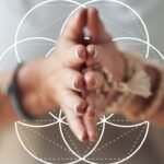 Hands held in a mindful prayer position over the Seed of Life symbol, representing inner guidance, self-awareness and conscious reflection.