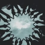 Silhouette of people forming a star with hands against a cloudy sky.
