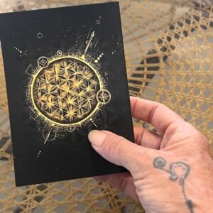 Hand holding The Soul Compass collectible postcard featuring the black and gold Quantum Consciousness artwork.