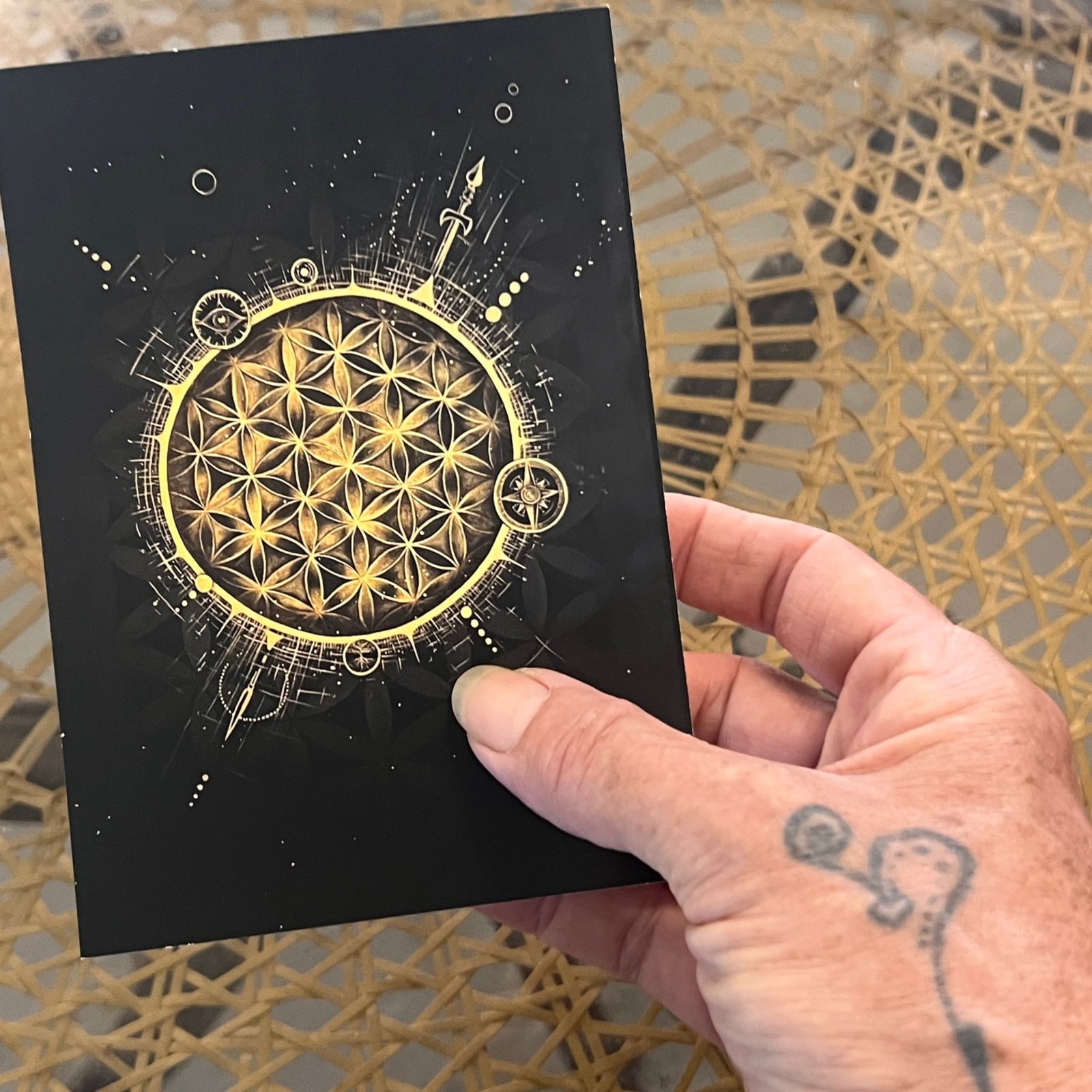 Hand holding The Soul Compass collectible postcard featuring the black and gold Quantum Consciousness artwork.
