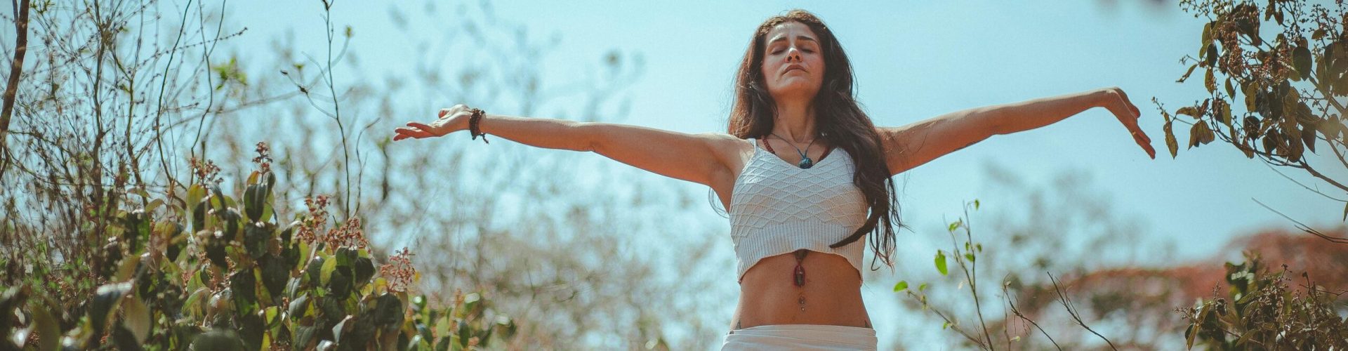 Peaceful scene of a woman meditating outdoors in a sunny summer setting, embodying wellness and tranquility.